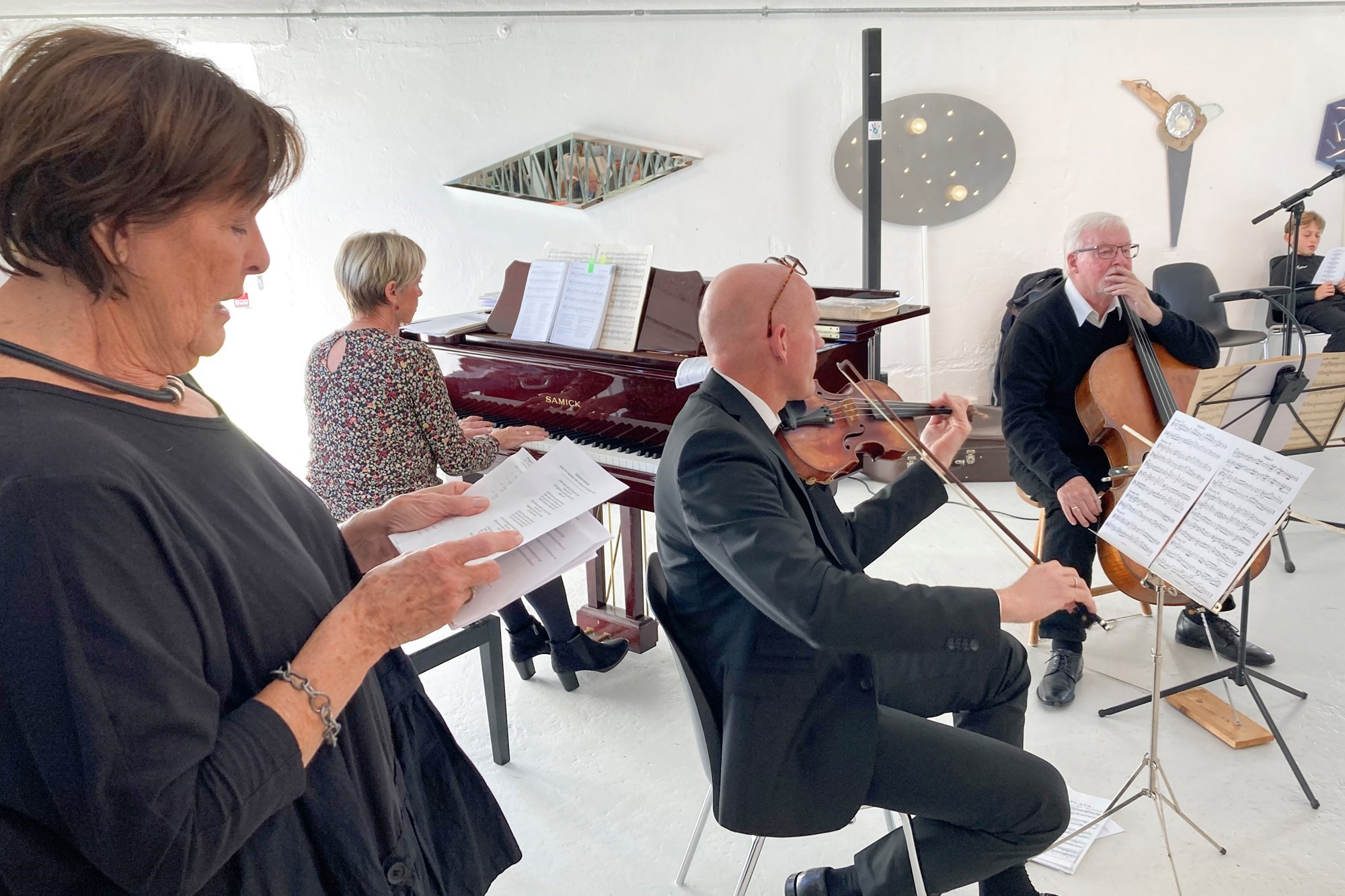 Musikere spiller klaver og violin og der synges