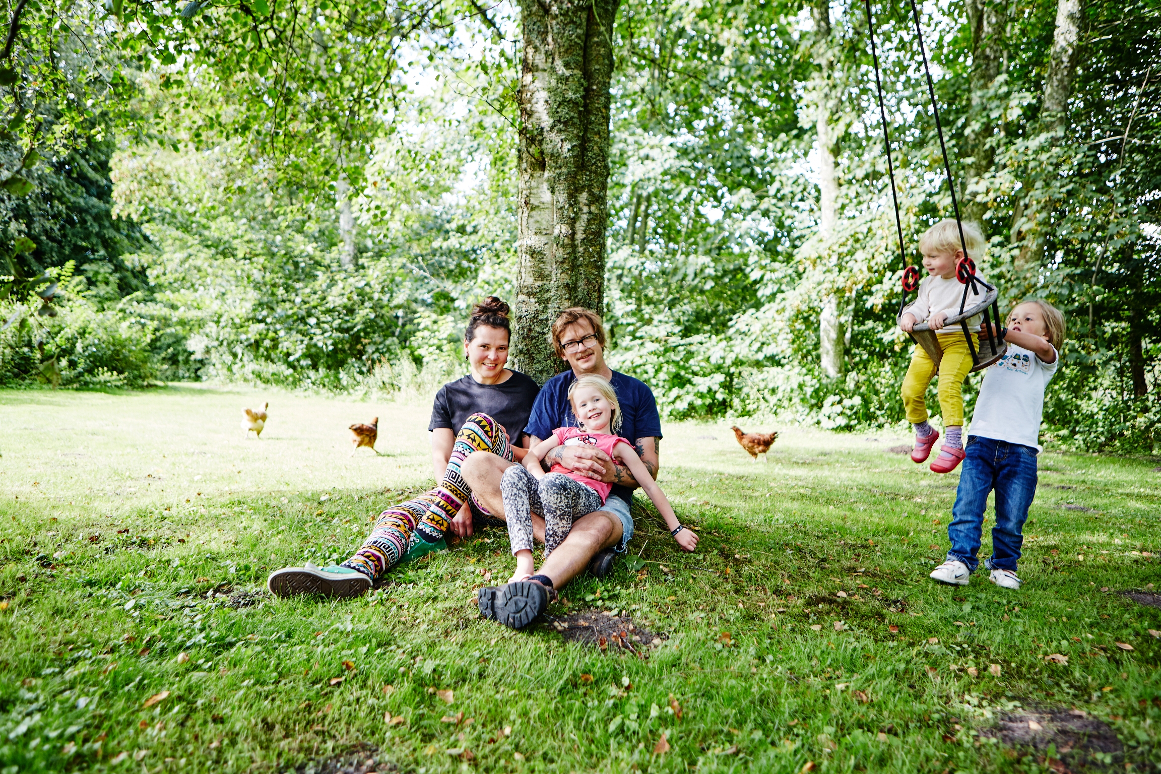 Familie sidder op af træ og børn gynger