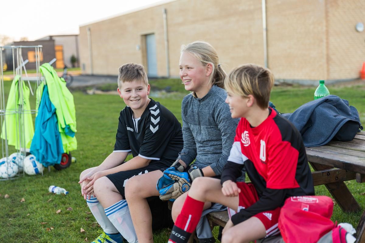 Tre fodboldspillere sidder på bænk