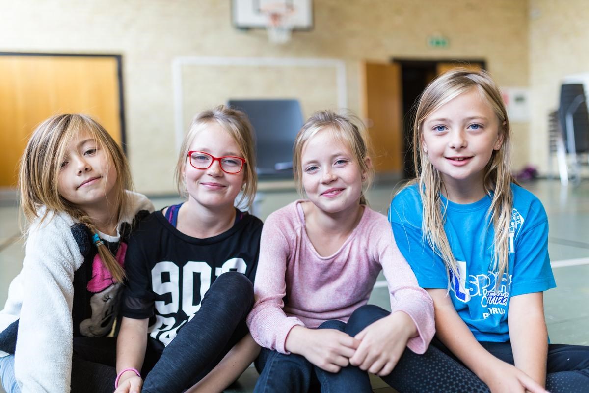 Fire piger sidder i gymnastiksal