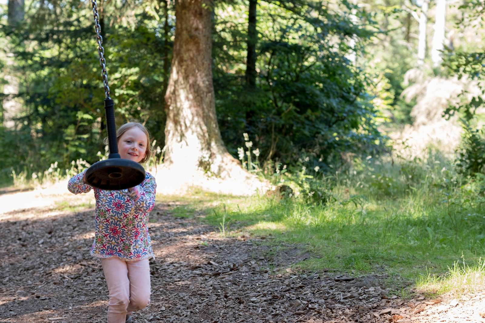 Pige leger med svævebane i skov