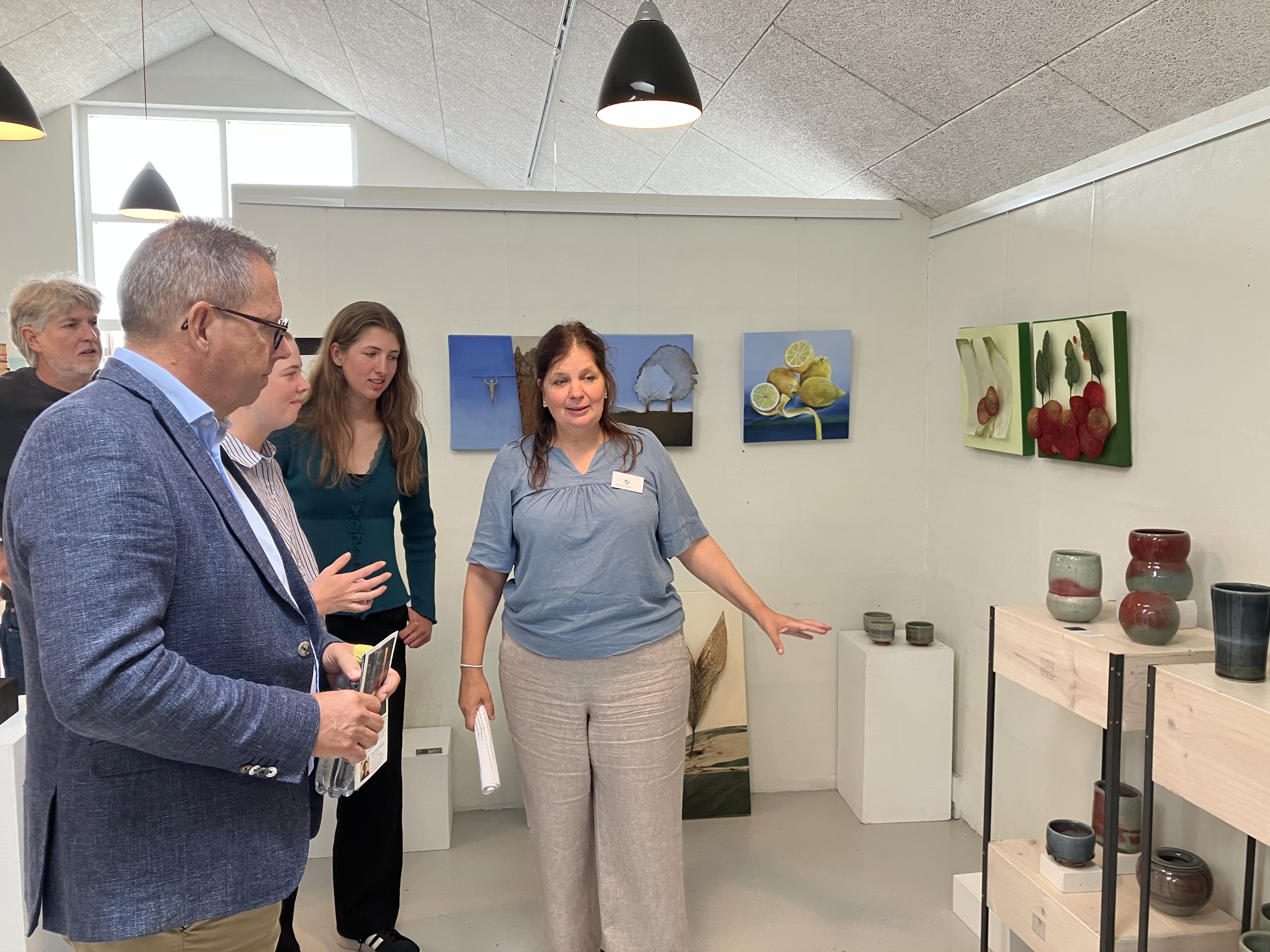 Billedkunstner Jeanette Nørlev, Gjøl, viser borgmester Christian Hem rundt i udstillingen. Keramikken på foto er lavet af keramiker Renate Langhein, Stadt Tornesch, og værkerne på væggen er lavet billedkunstner Elke Werner, Stadt Tornesch.