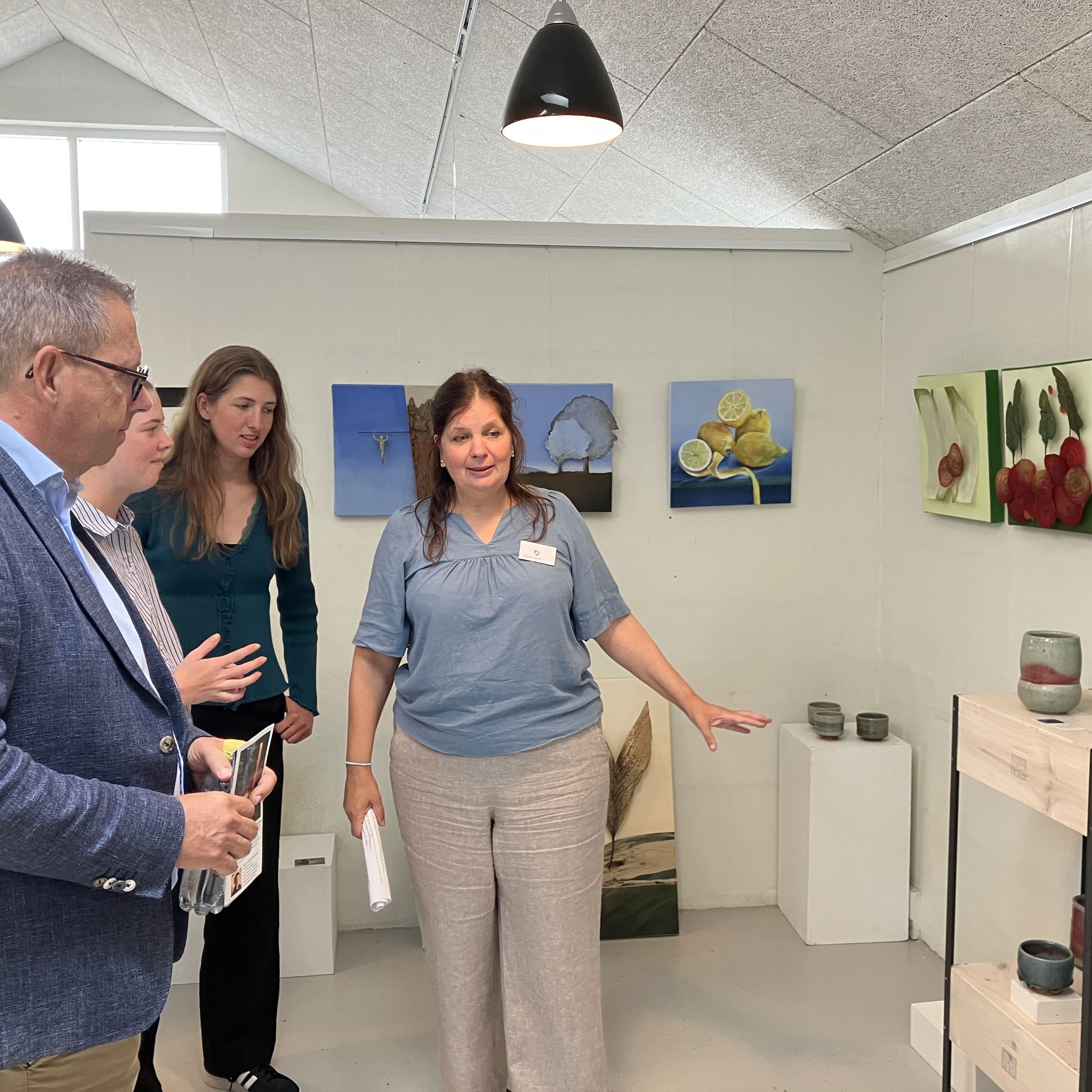 Billedkunstner Jeanette Nørlev, Gjøl, viser borgmester Christian Hem rundt i udstillingen. Keramikken på foto er lavet af keramiker Renate Langhein, Stadt Tornesch, og værkerne på væggen er lavet billedkunstner Elke Werner, Stadt Tornesch.