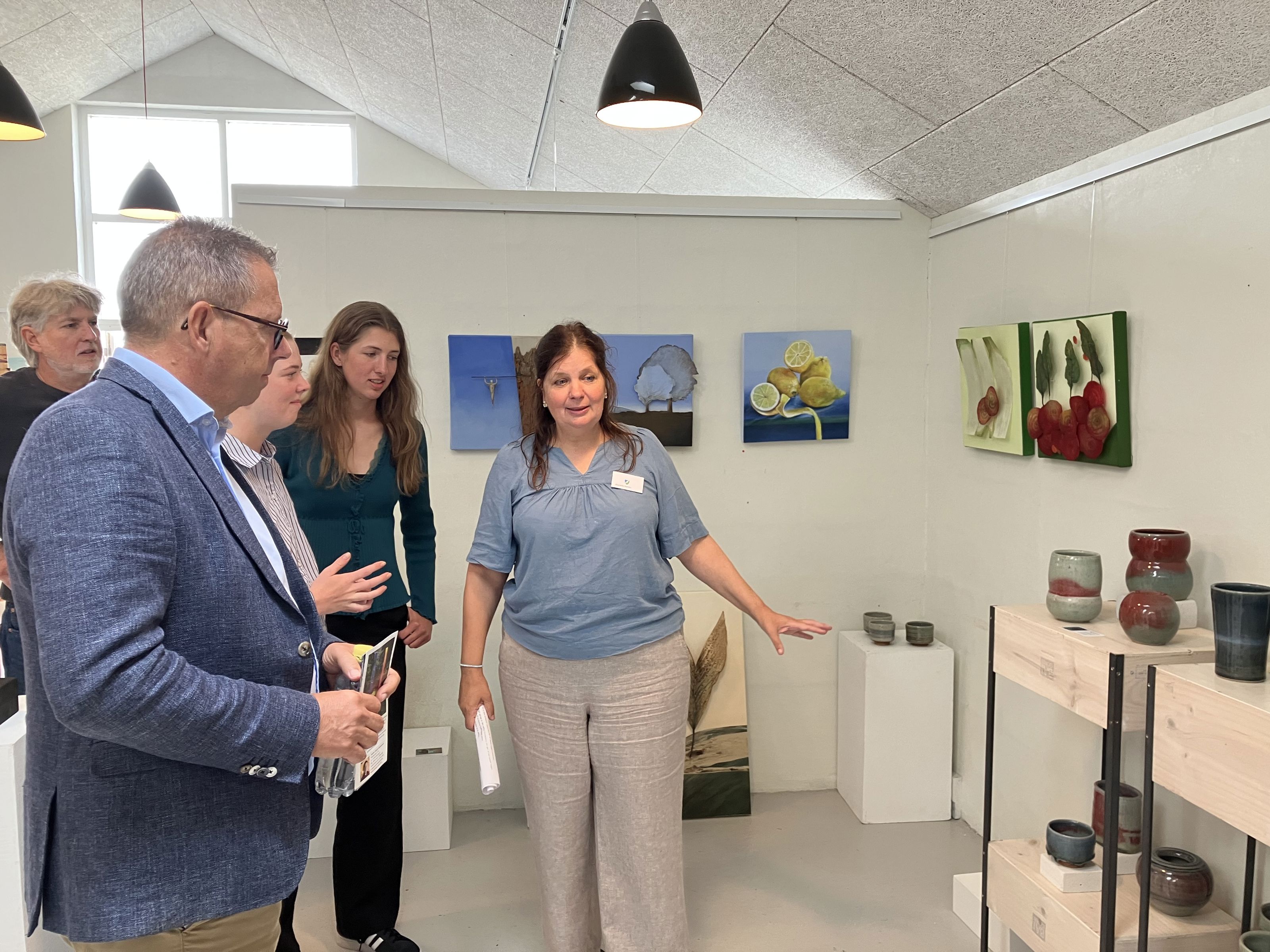 Billedkunstner Jeanette Nørlev, Gjøl, viser borgmester Christian Hem rundt i udstillingen. Keramikken på foto er lavet af keramiker Renate Langhein, Stadt Tornesch, og værkerne på væggen er lavet billedkunstner Elke Werner, Stadt Tornesch.