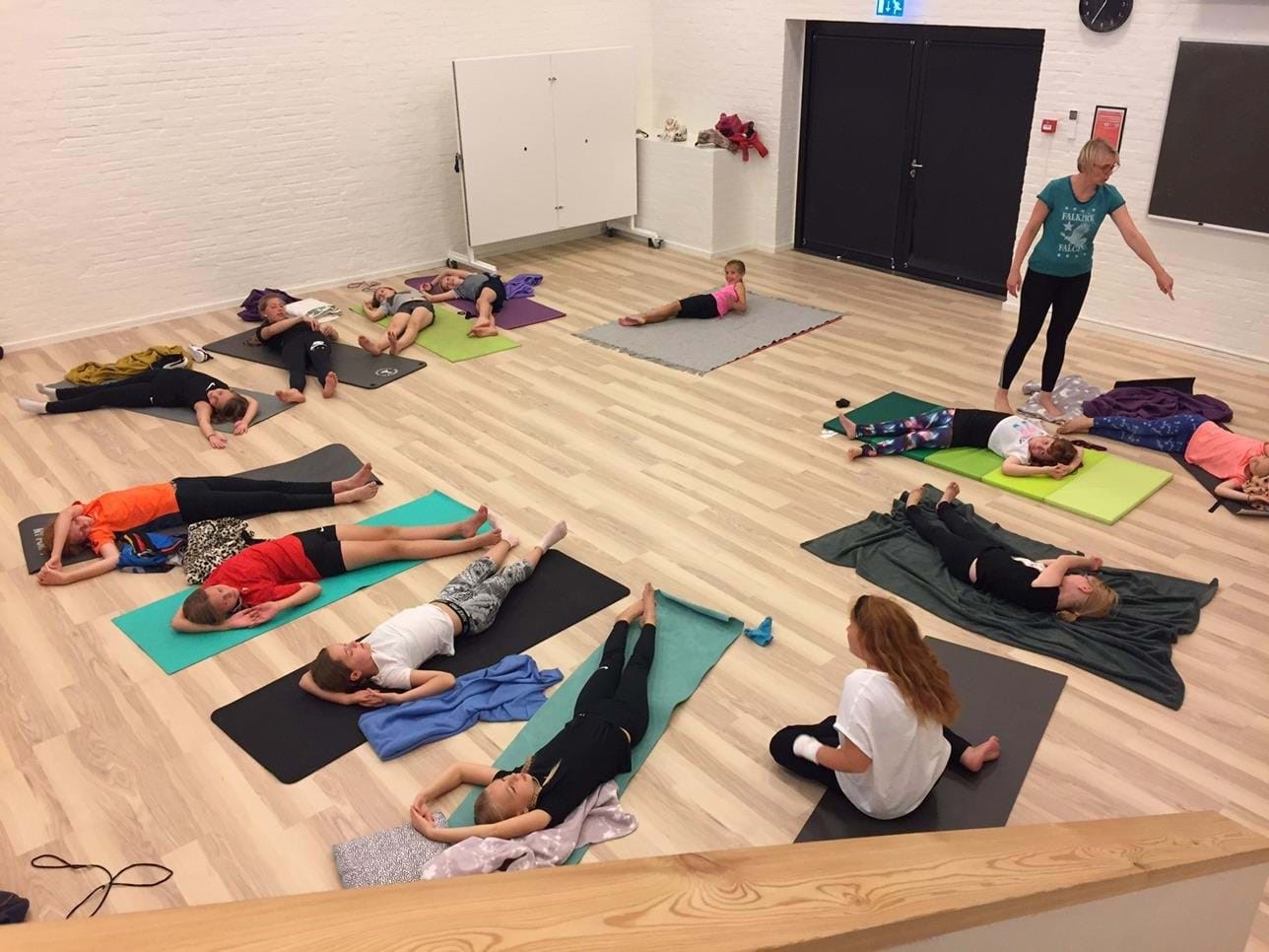 Børn ligger i rundkreds på gulvet