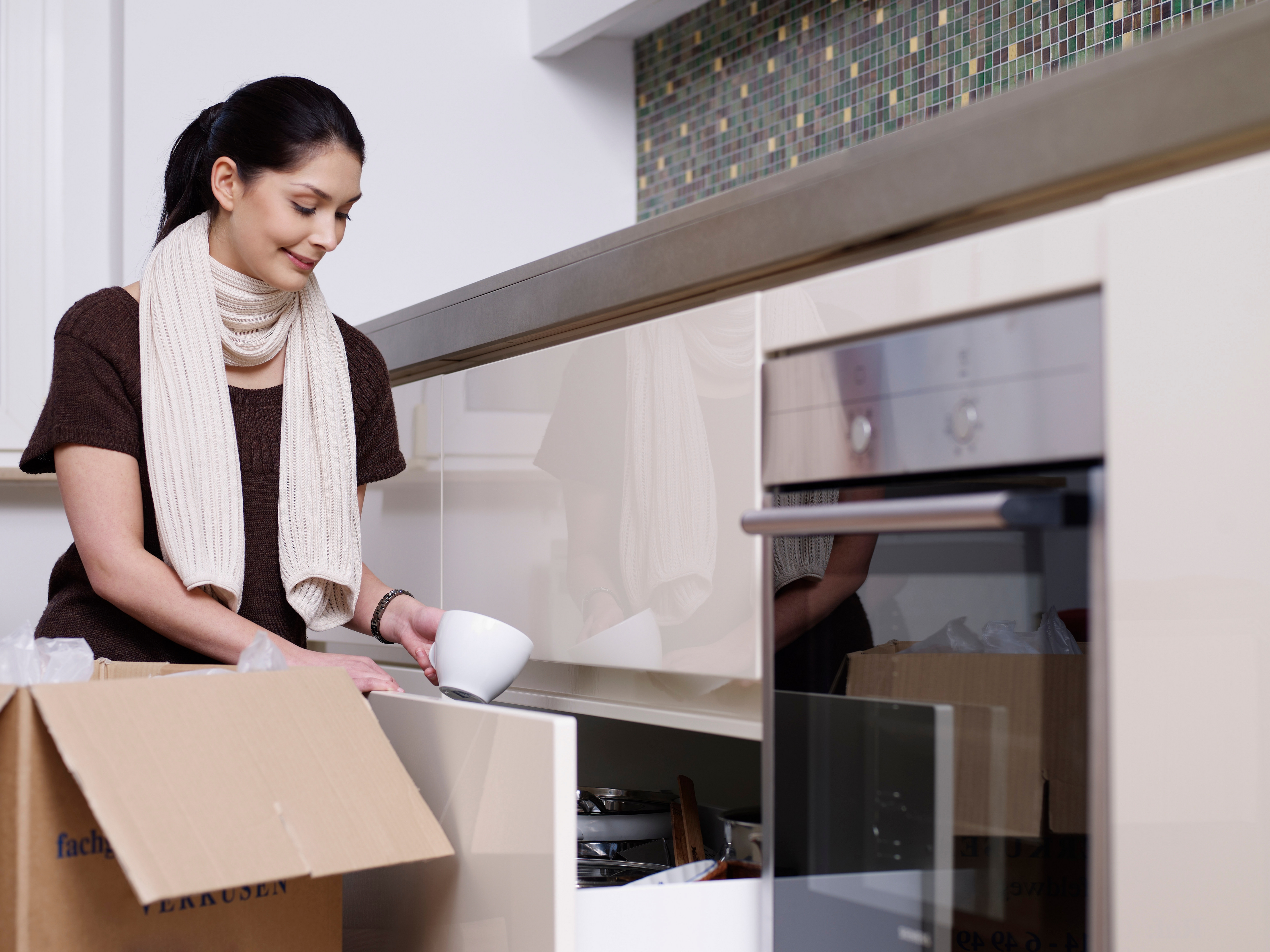 Kvinde med flyttekasse tømmer skabe