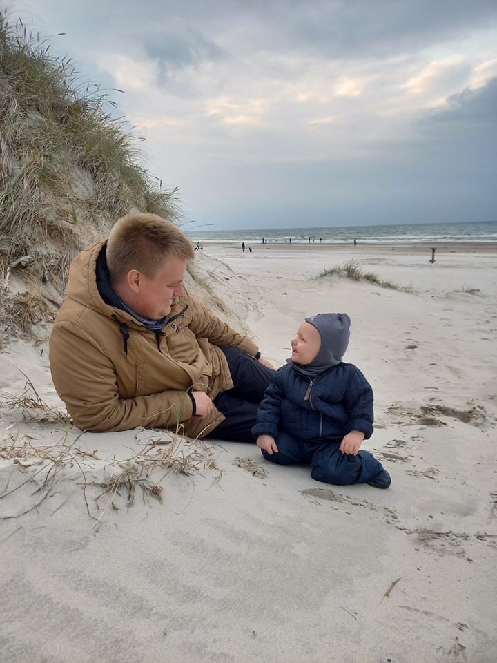 Far med spædbarn på stranden