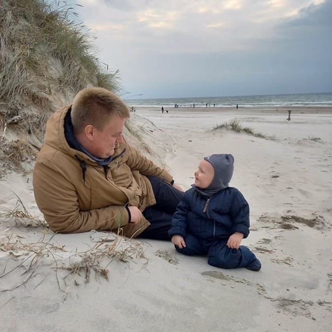 Far med spædbarn på stranden