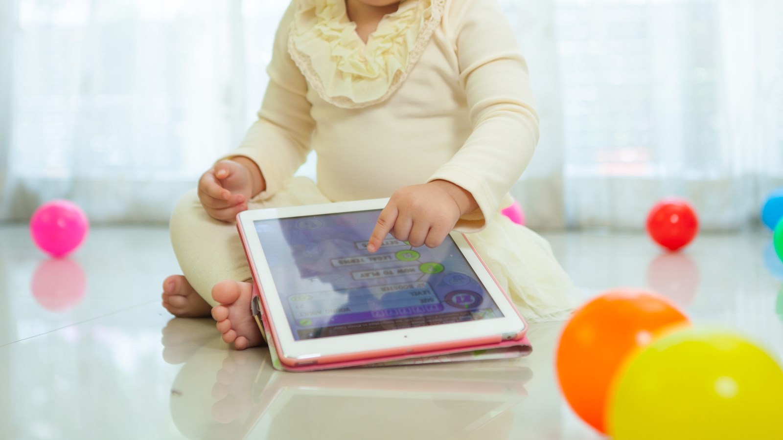 Et lille barn leger med en tablet.