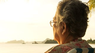 Ældre kvinde ser eftertænksomt ud i horisonten