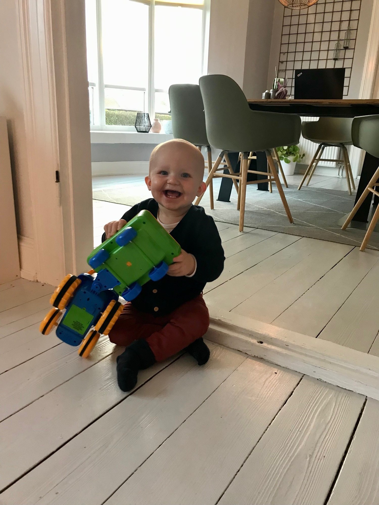 Storsmilende barn leger med plastik traktor