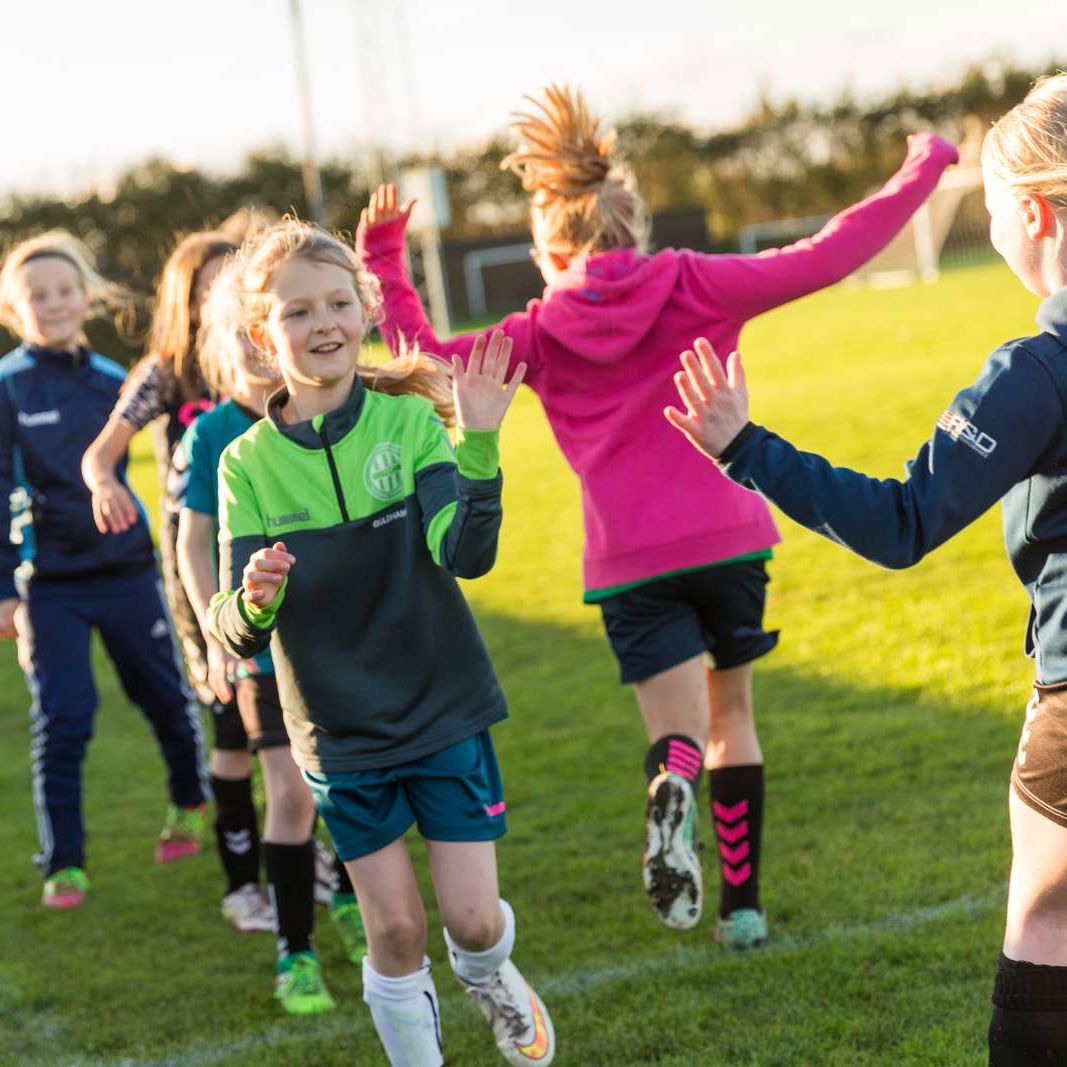pige fodboldspillere hilser på modstandere