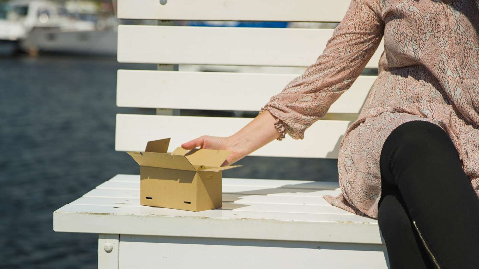 Kvinde med lille flyttekasse på bænk