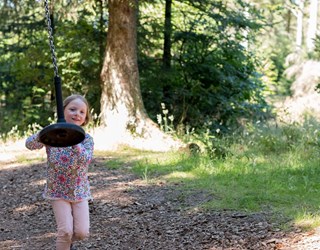 Pige leger med svævebane i skov