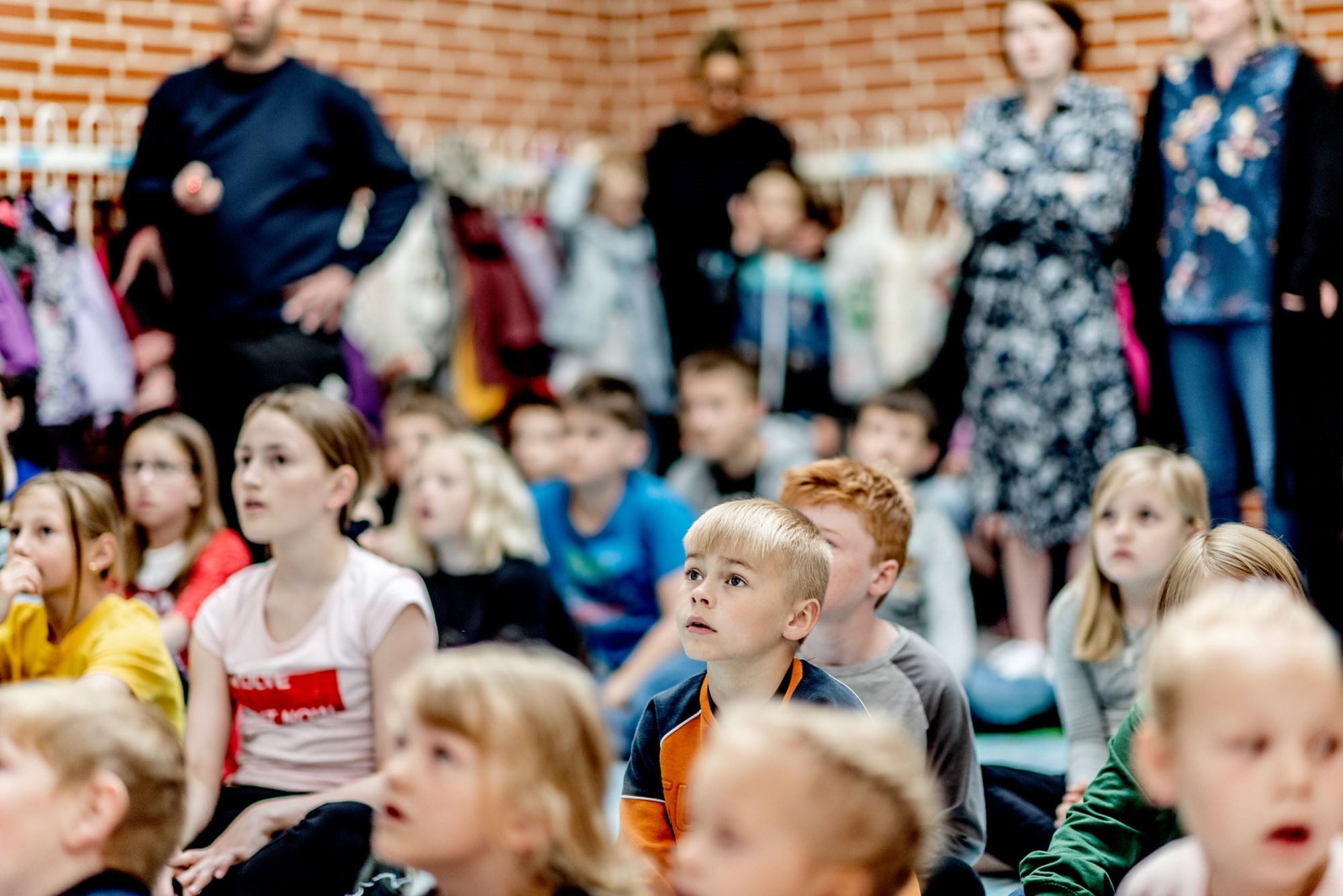 Børn lytter efter i forsamlingssal