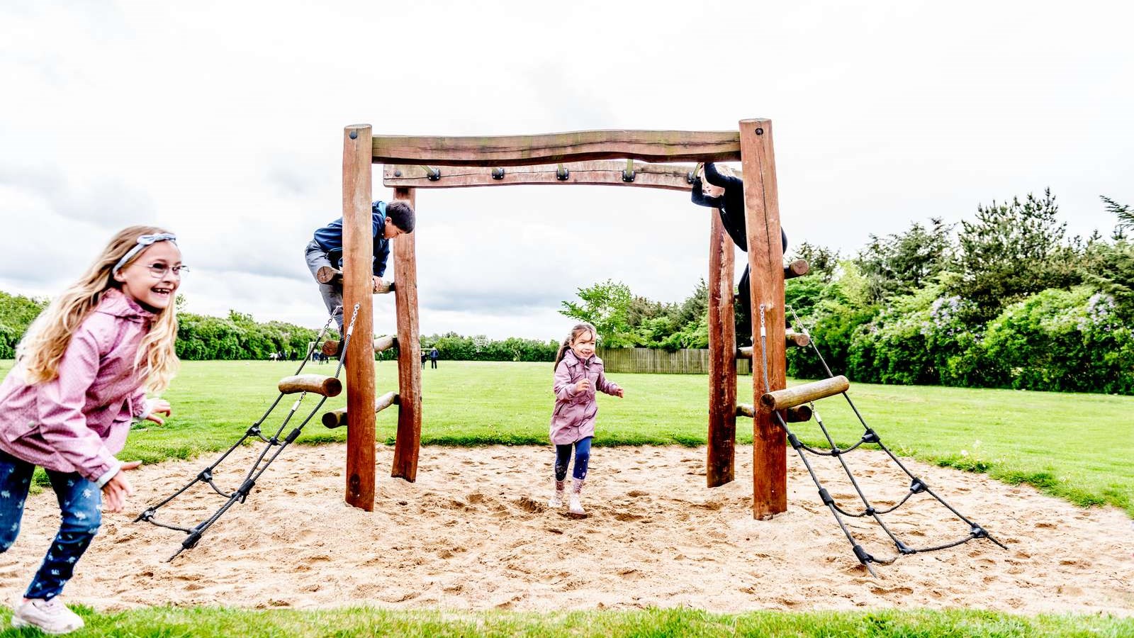 Børn klatrer og leger på legeplads