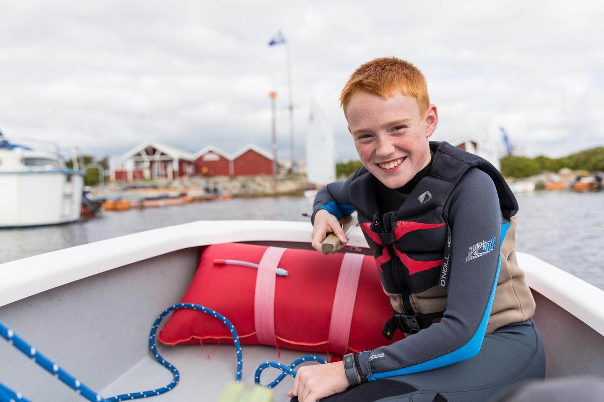 Dreng styrer roret i lille båd