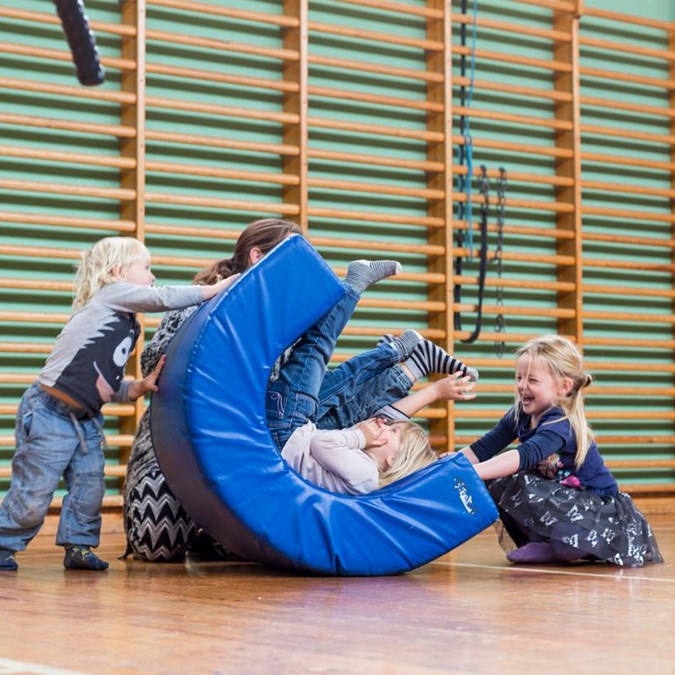Børn og forælder leger på redskab i gymnastiksal